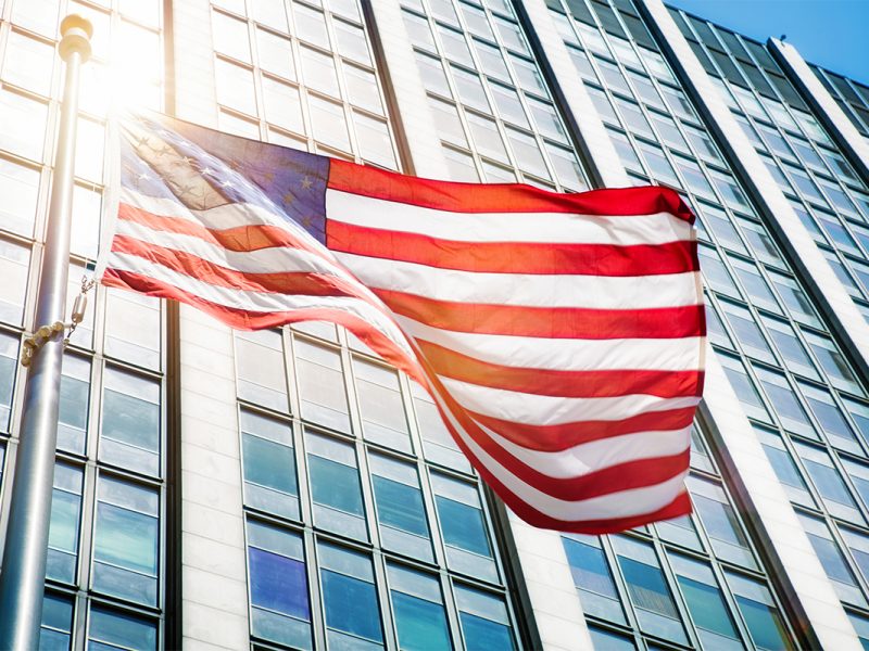Floating American flag in front of office building sun flare